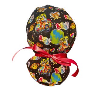 May include: A black scrub hat with a colorful print of aliens, hearts, and smiley faces. The hat is tied with a red ribbon.