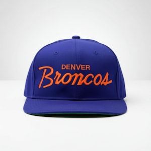 May include: A royal blue baseball cap with the word "Denver" above the word "Broncos" in orange script. The cap has a flat brim and a green underside.
