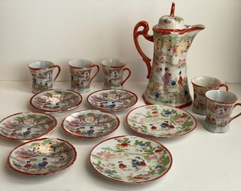 May include: A vintage Japanese tea set with a red and white floral design. The set includes a teapot, six cups, and six saucers.