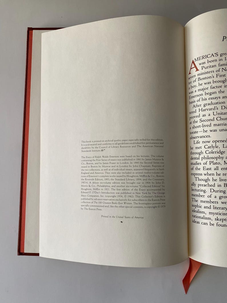Puede incluir: Libro abierto con lomo rojo y marcap&aacute;ginas melocot&oacute;n. Las p&aacute;ginas son color crema con texto negro. El texto detalla la impresi&oacute;n del libro, el autor y los ensayos.