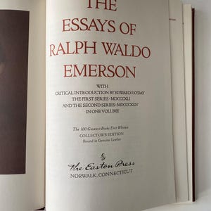 Puede incluir: Libro abierto titulado "The Essays of Ralph Waldo Emerson" con letras rojas. El libro es una edici&oacute;n de coleccionista encuadernada en cuero genuino, publicado por The Easton Press en Norwalk, Connecticut. Una cinta roja como marcador de libro es visible.