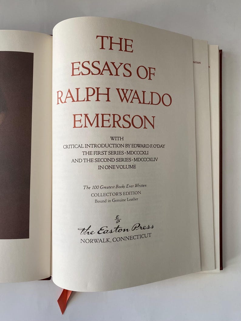 Puede incluir: Libro abierto titulado "The Essays of Ralph Waldo Emerson" con letras rojas. El libro es una edici&oacute;n de coleccionista encuadernada en cuero genuino, publicado por The Easton Press en Norwalk, Connecticut. Una cinta roja como marcador de libro es visible.