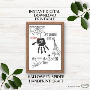 Puede incluir: Un imprimible enmarcado con temática de Halloween con un diseño de araña de huella de mano. La araña negra está suspendida de una telaraña, con el texto "Happy Halloween" y "Just Dropping In To Say". Las palabras "Instant Digital Download Printable" están en la parte superior.