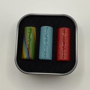 May include: A white ceramic mug with a black handle and the text "But First, Coffee" in a black, bold font. The mug is on a white surface.