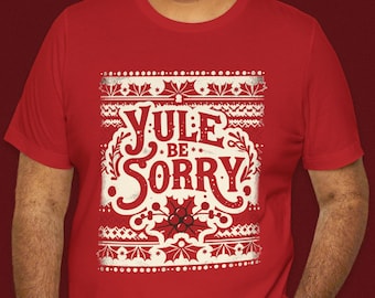 May include: Red t-shirt with a white Christmas-themed design. The design features a white snowflake pattern, a holly sprig, and the text "Yule Be Sorry".