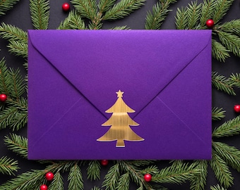 May include: A purple envelope with a gold Christmas tree design. The envelope is surrounded by green pine branches with red berries.