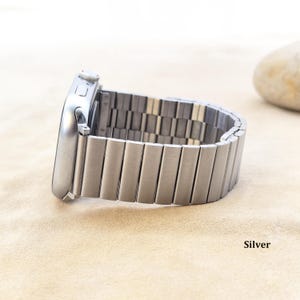 May include: A silver-colored smartwatch with a metallic link band featuring a brushed finish. The watch case is rectangular with rounded corners and a side crown. The word Silver is printed in the lower right corner of the image.