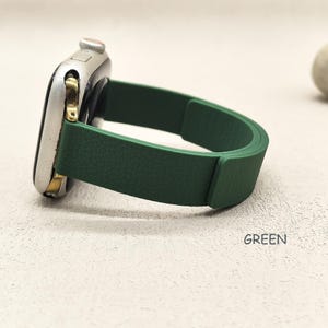 May include: A silver smartwatch with a green band. The band is a solid, textured green color. The word "GREEN" is printed in white on the surface.