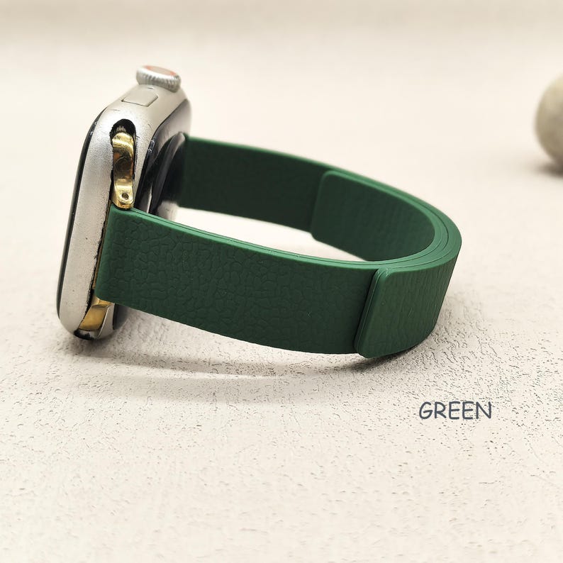 May include: A silver smartwatch with a green band. The band is a solid, textured green color. The word "GREEN" is printed in white on the surface.