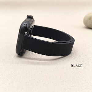 May include: Black smartwatch with a black band. The watch face is dark and sleek, with a textured black band. The word "BLACK" is printed in white on the surface.
