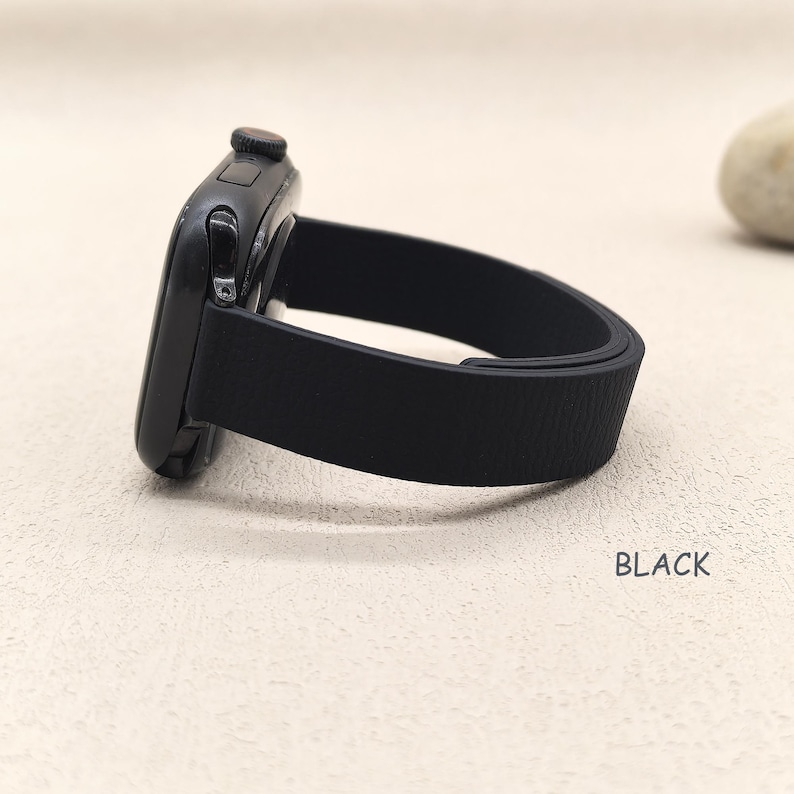May include: Black smartwatch with a black band. The watch face is dark and sleek, with a textured black band. The word "BLACK" is printed in white on the surface.