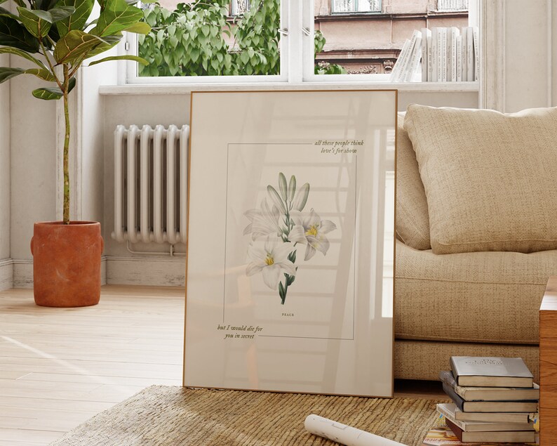 Pu&ograve; includere: Una stampa incorniciata con un'illustrazione di un fiore bianco e una citazione che recita "Tutte queste persone pensano che l'amore sia per lo spettacolo, ma io morirei per te in segreto."