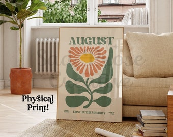 Op de afbeelding: Een vintage poster met het woord "AUGUSTUS" in vetgedrukte groene letters. De poster toont een gestileerde illustratie van een bloem met oranje en roze bloemblaadjes en groene bladeren. De tekst "VERLOREN IN DE HERINNERING" is onder de bloem gedrukt.