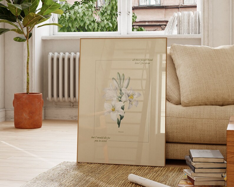 Pu&ograve; includere: Una stampa incorniciata con un'illustrazione di un fiore bianco e il testo "All these people think love's for forever, but I would die for you in secret."