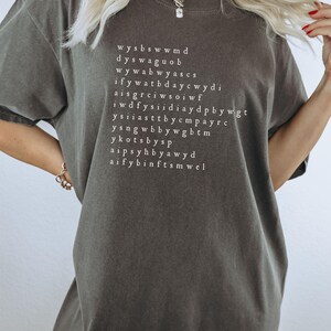 K&ouml;nnte beinhalten: Ein dunkelgraues T-Shirt mit wei&szlig;em Text, der lautet: "wysbswwmd dyswagUOB wywabwyascs ifywatbdaycwydi aisgrciwsoiwf iwdffysidiaydpbbywgt ysiiaasttbdycpayrc ysnqwbbywgbtm ykotsbysp aipsyhbbyawyd aifybinftsmwel"