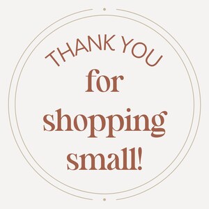 May include: A circular sticker with a light beige background and a thin circular border. The text 'THANK YOU for shopping small!' is printed in the center in a dark terracotta serif font, with the words stacked in four distinct lines.