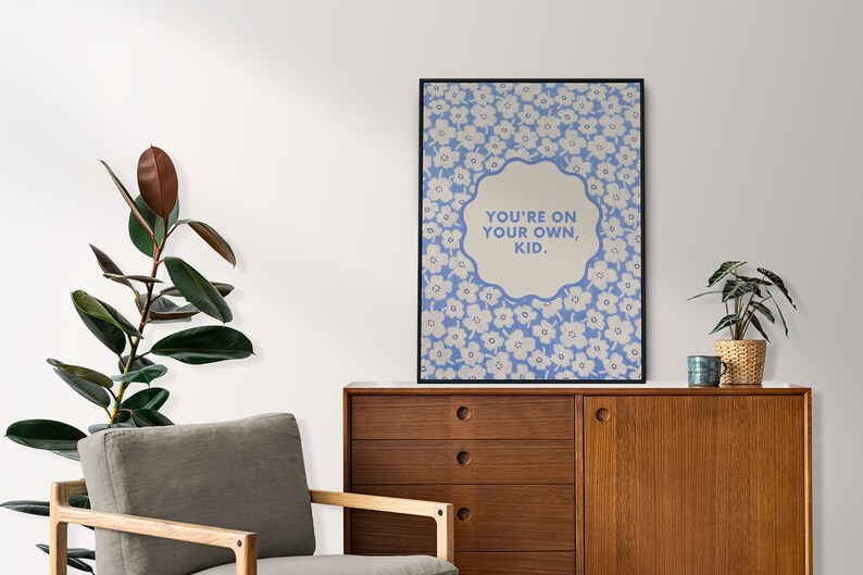 May include: A framed print with a blue background and white flowers. The print features a white speech bubble with the text "YOU'RE ON YOUR OWN, KID."