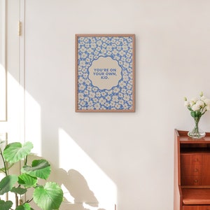May include: A framed print with a blue and white floral pattern and the text "You're on your own, kid." in a white circle.