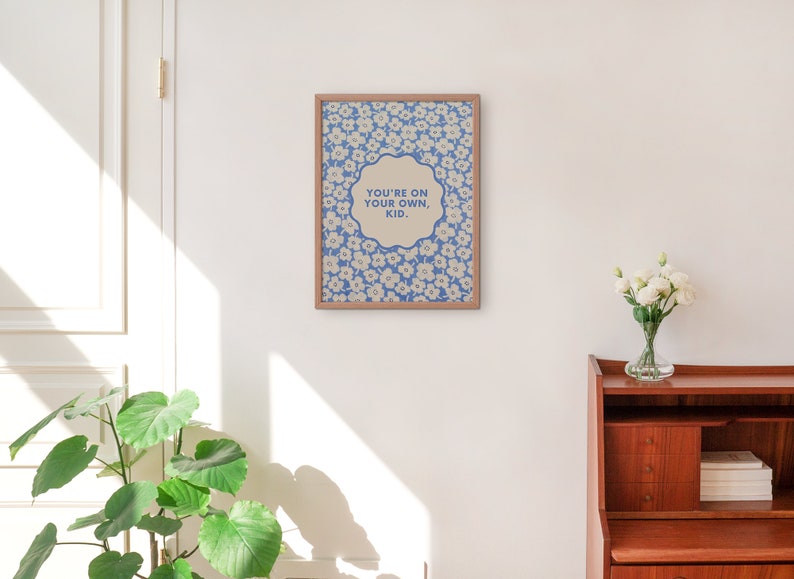 May include: A framed print with a blue and white floral pattern and the text "You're on your own, kid." in a white circle.