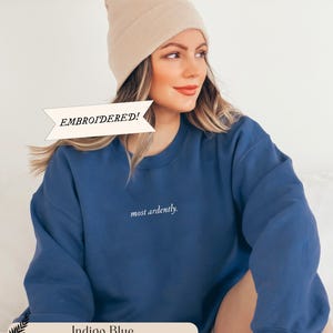 Puede incluir: Sudadera azul &iacute;ndigo con la inscripci&oacute;n bordada "most ardently". La sudadera se combina con un gorro beige. Tambi&eacute;n es visible el texto "EMBROIDERED!"