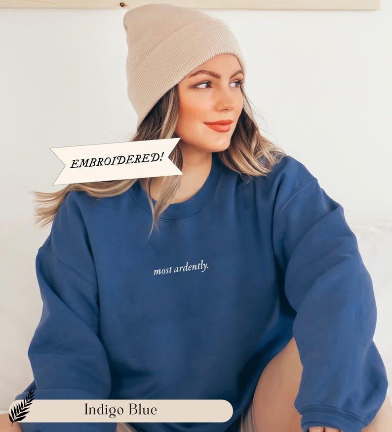 Puede incluir: Sudadera azul &iacute;ndigo con la inscripci&oacute;n bordada "most ardently". La sudadera se combina con un gorro beige. Tambi&eacute;n es visible el texto "EMBROIDERED!"
