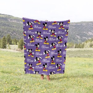 May include: Purple fleece blanket with a repeating pattern of Mickey Mouse and the name "Oliver" printed in white.