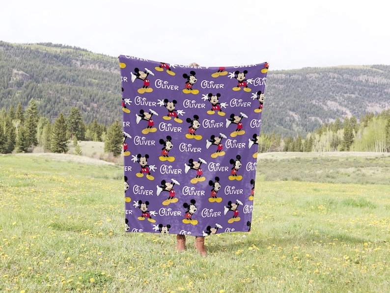 May include: Purple fleece blanket with a repeating pattern of Mickey Mouse and the name "Oliver" printed in white.