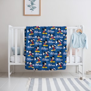May include: A blue baby blanket with a repeating pattern of Mickey Mouse and the name "Oliver".