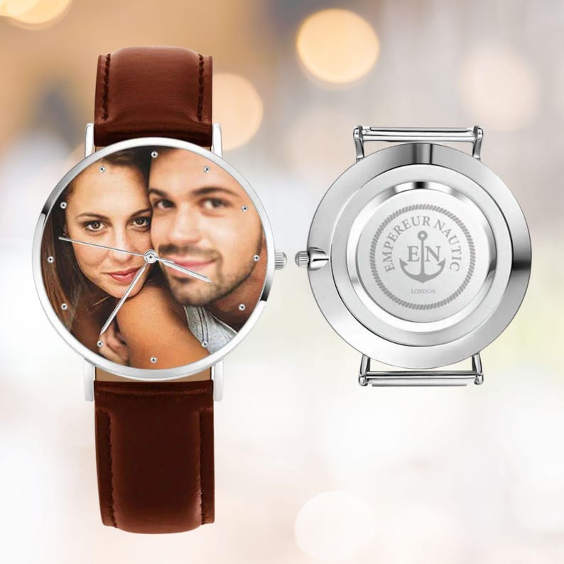 K&ouml;nnte beinhalten: Personalisierte Armbanduhr mit braunem Lederarmband und silberfarbenem Geh&auml;use. Das Zifferblatt zeigt ein Foto eines Paares. Auf der R&uuml;ckseite der Uhr sind die Worte "EMPEREUR NAUTIC" und ein Ankersymbol eingraviert.