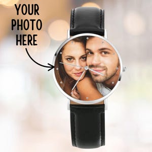 K&ouml;nnte beinhalten: Eine personalisierte Armbanduhr mit schwarzem Lederarmband und silberfarbenem Geh&auml;use. Das Zifferblatt zeigt ein Foto eines Paares. Der Text "YOUR PHOTO HERE" befindet sich &uuml;ber dem Zifferblatt.