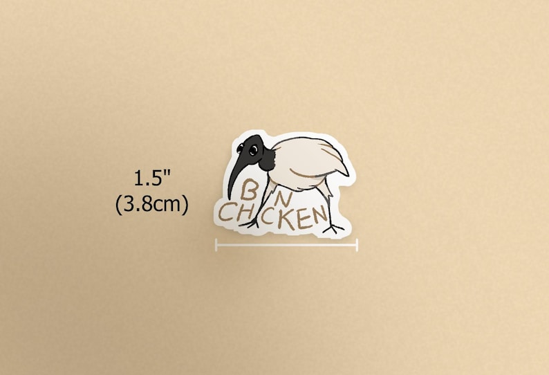 K&ouml;nnte beinhalten: Aufkleber mit einem Cartoon-Ibis-Vogel mit schwarzem Kopf und Schnabel und wei&szlig;em K&ouml;rper. Der Text "BAN CHICKEN" steht unter dem Vogel. Der Aufkleber ist 3,8 cm lang.