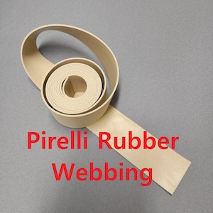 May include: A roll of beige Pirelli Rubber Webbing, unrolled on a gray surface. The text "Pirelli Rubber Webbing" is printed in red across the bottom of the image. The webbing is coiled in a spiral.