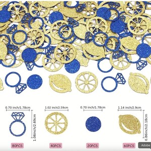 May include: A scattering of gold and blue glitter confetti in assorted shapes, such as circles, lemon slices, diamond rings, and lemon wheel designs. The confetti pieces vary in size, with the largest being 2.9 cm long.