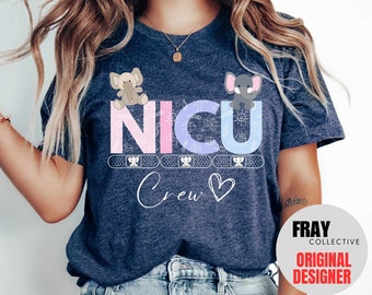 May include: A navy blue t-shirt with the text "NICU Crew" in pink, blue, and white. The letters are decorated with small elephant illustrations and band-aid designs. A heart symbol is next to the word "Crew".