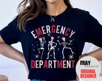 May include: Black t-shirt with a white and pink graphic of three skeletons wearing Santa hats and dancing. The text "Emergency Department" is written below the skeletons. The text "Fray Collective Original Designer" is in a white circle with a red border.