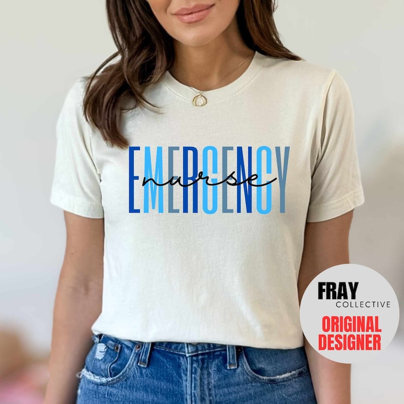 Puede incluir: Una camiseta blanca con el texto "EMERGENCY nurse" en letras azules y negras. El texto est&aacute; apilado verticalmente con la palabra "nurse" escrita en cursiva.