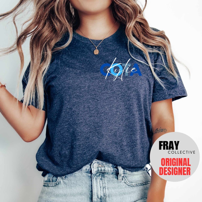 May include: A navy blue t-shirt with a blue and white graphic design that says "Kylie" on the front. The shirt is made of a soft, comfortable material and has a relaxed fit.