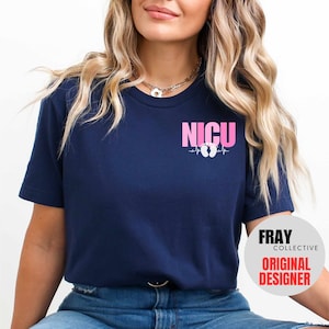 Pu&ograve; includere: Una maglietta blu navy con il testo "NICU" in lettere rosa e un grafico di battito cardiaco rosa con impronte di piedi di bambino. Il testo "FRAY COLLECTIVE ORIGINAL DESIGNER" &egrave; visibile nell'angolo in basso a destra.