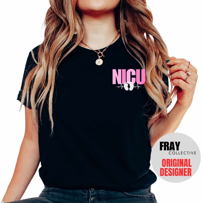Pu&ograve; includere: Maglietta nera con il testo "NICU" in lettere rosa e un grafico del battito cardiaco con impronte di piedi rosa. Il testo "FRAY COLLECTIVE ORIGINAL DESIGNER" &egrave; su un cerchio bianco nell'angolo in basso a destra.