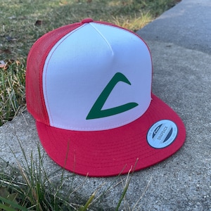 May include: A red and white trucker hat with a green triangle logo. The hat has a mesh back and a snap closure.