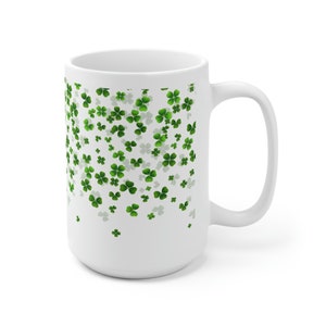 May include: White ceramic mug with a design of green four-leaf clovers scattered across the surface.