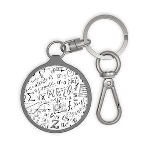 Peut inclure: Un porte-clés rond gris avec un mousqueton et un anneau argenté. Le porte-clés présente un fond blanc avec des formules mathématiques noires et le mot "MATH". Un cadeau pour les passionnés de mathématiques.