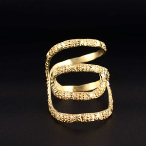 Puede incluir: Un anillo de oro con un diseño de triple banda. Cada banda está decorada con un patrón repetitivo de pequeñas flores.