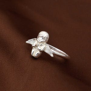 May include: A white ceramic mug with a wraparound design featuring a vibrant, colorful illustration of various mushrooms. The mug has a black handle and a glossy finish. The text "Shroom Queens" is printed on the mug.