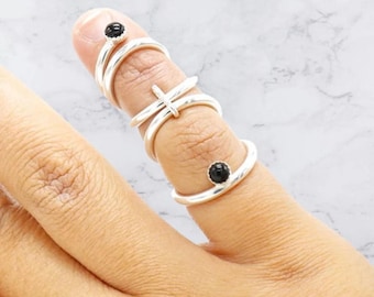 Op de afbeelding: Drie zilveren ringen met zwarte edelstenen. De ringen zijn op een vinger gestapeld. De ringen zijn eenvoudig en elegant.
