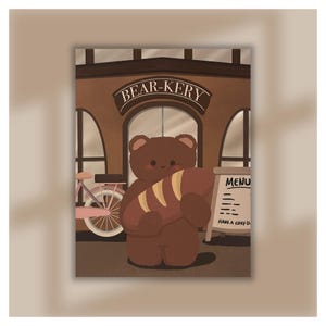 Op de afbeelding: Een bruine beer die een brood vasthoudt voor een bakkerij genaamd "BEAR-KERY". De bakkerij heeft een roze fiets voor de deur en een menu-bord met de tekst "HAVE A COSY DAY".
