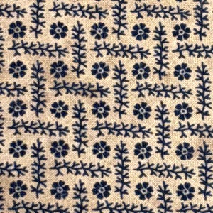 Puede incluir: Primer plano de una tela con un patr&oacute;n repetitivo de motivos florales y de hojas azul marino sobre un fondo beige. El dise&ntilde;o presenta peque&ntilde;as flores estilizadas y delicados elementos en forma de rama dispuestos en una formaci&oacute;n similar a una cuadr&iacute;cula.