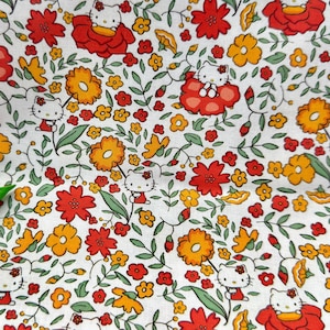 May include: White fabric with a repeating pattern of red, orange, and yellow flowers, green leaves, and Hello Kitty characters in red dresses. The design is a floral pattern.