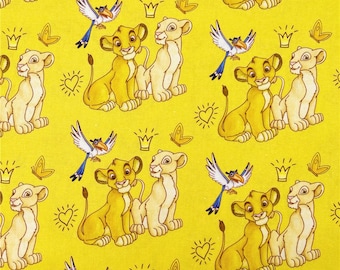 May include: Yellow fabric featuring a repeating pattern of cartoon lions, birds, crowns, hearts, and butterflies. The lions are in shades of yellow and tan. The birds have blue and white wings. The crowns are gold.