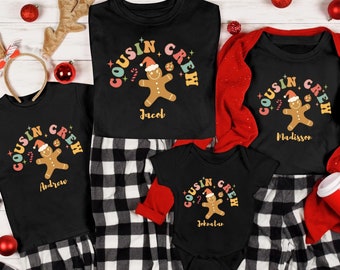 May include: Four black t-shirts with a gingerbread man graphic and the text "Cousin Crew" in rainbow letters. Each shirt has a different name printed below the graphic: Andrew, Jacob, Madisson, and Johratar.